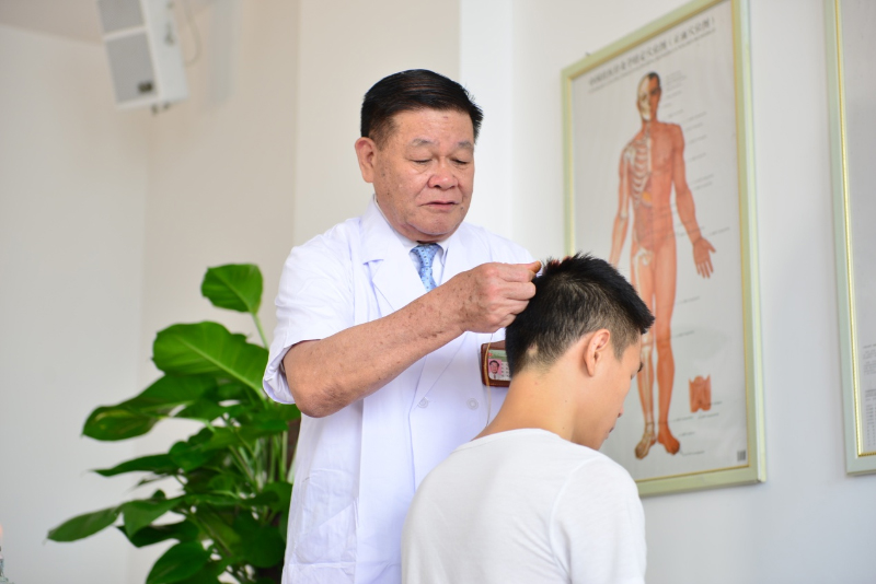 国医大师黄瑾明为患者进行壮医药线点灸疗法治疗。广西中医药大学供图